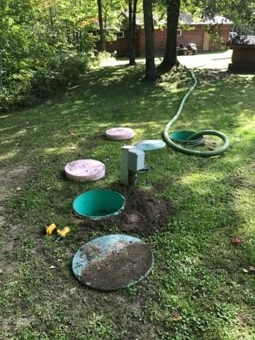 Septic tank being drained with a green hose